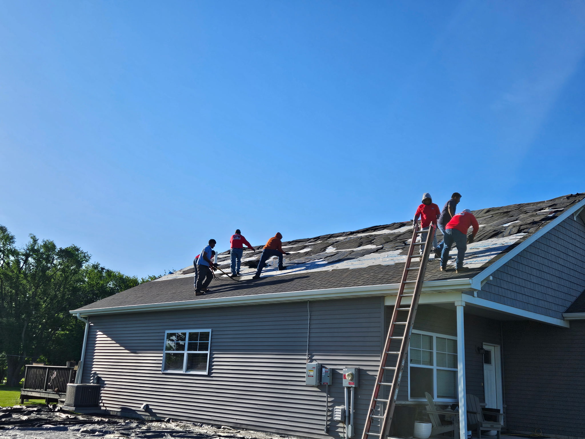 Roof tear-off crew removing old shingles Iowa